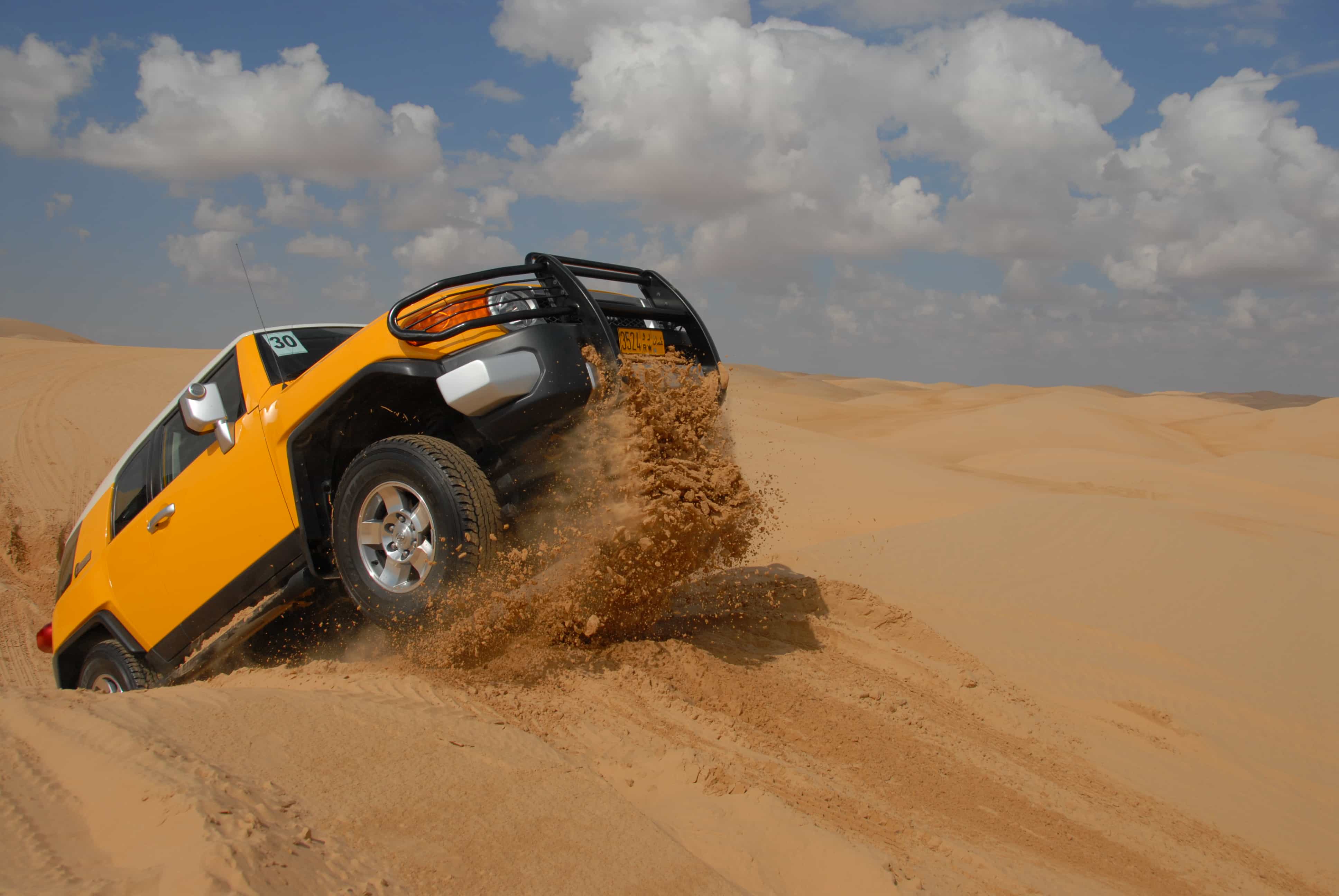 Car driving up dune