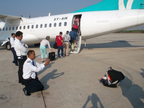 pilot taking photo of baby in Maxi Cosi in front of airplane