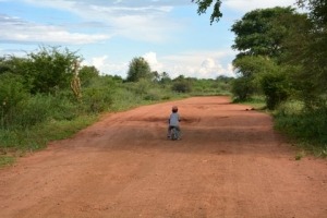 child riding bike on red dirt road, travel with kids, Puky Laufrad